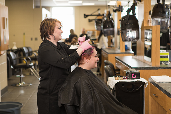 A cosmetology student practices cutting hair