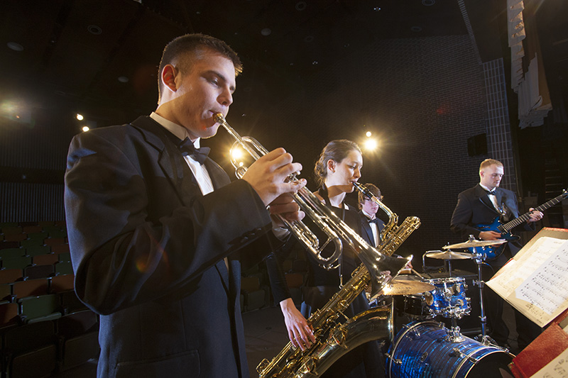 A student in black tie plays trumpet