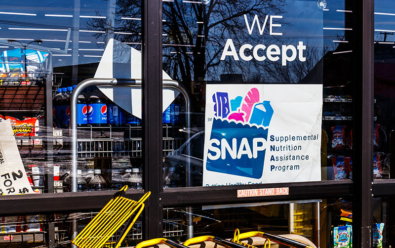 A shop window sign says We Accept SNAP