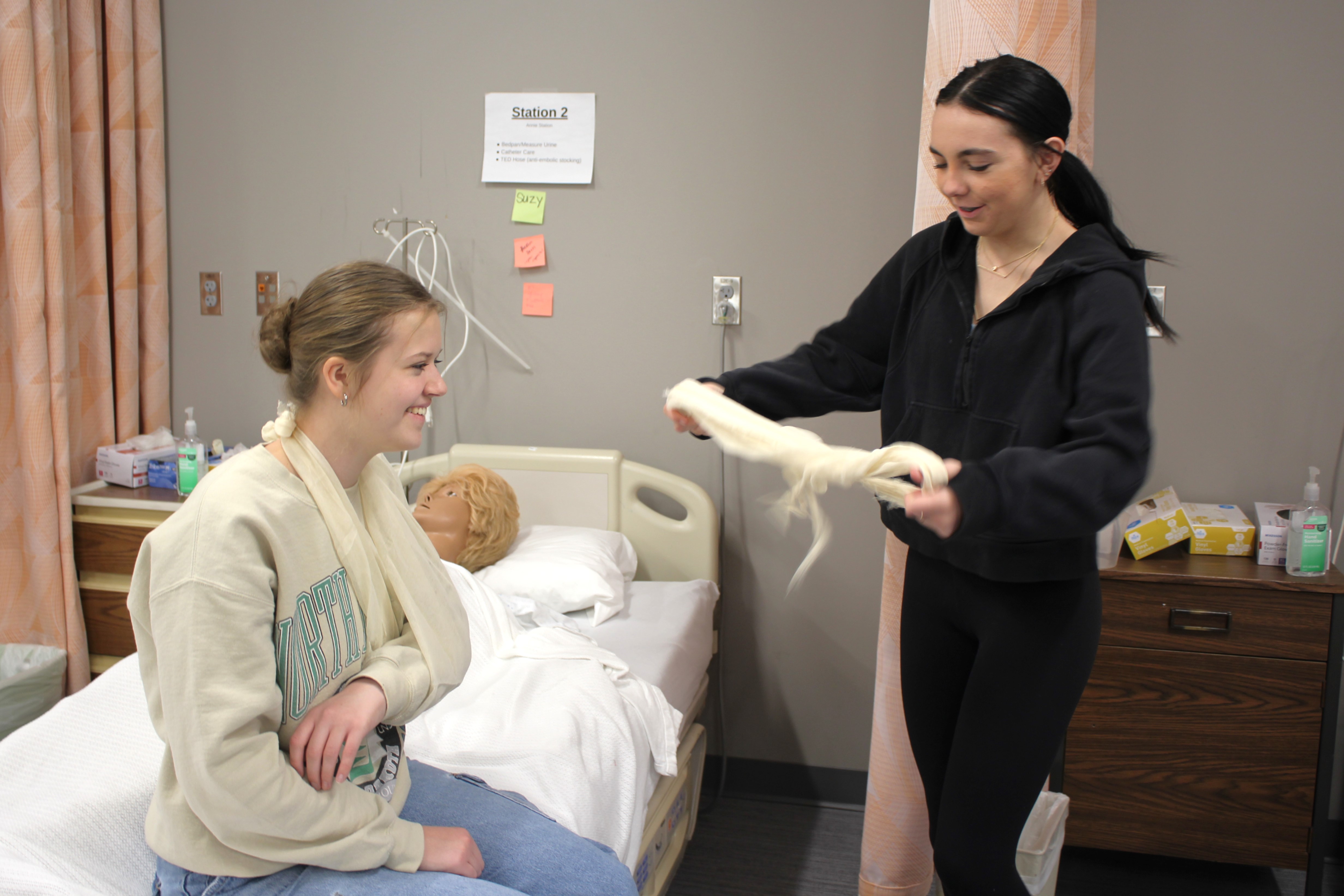 Rowan Myatt, right, fashions a sling for Leah Muehler’s arm. 