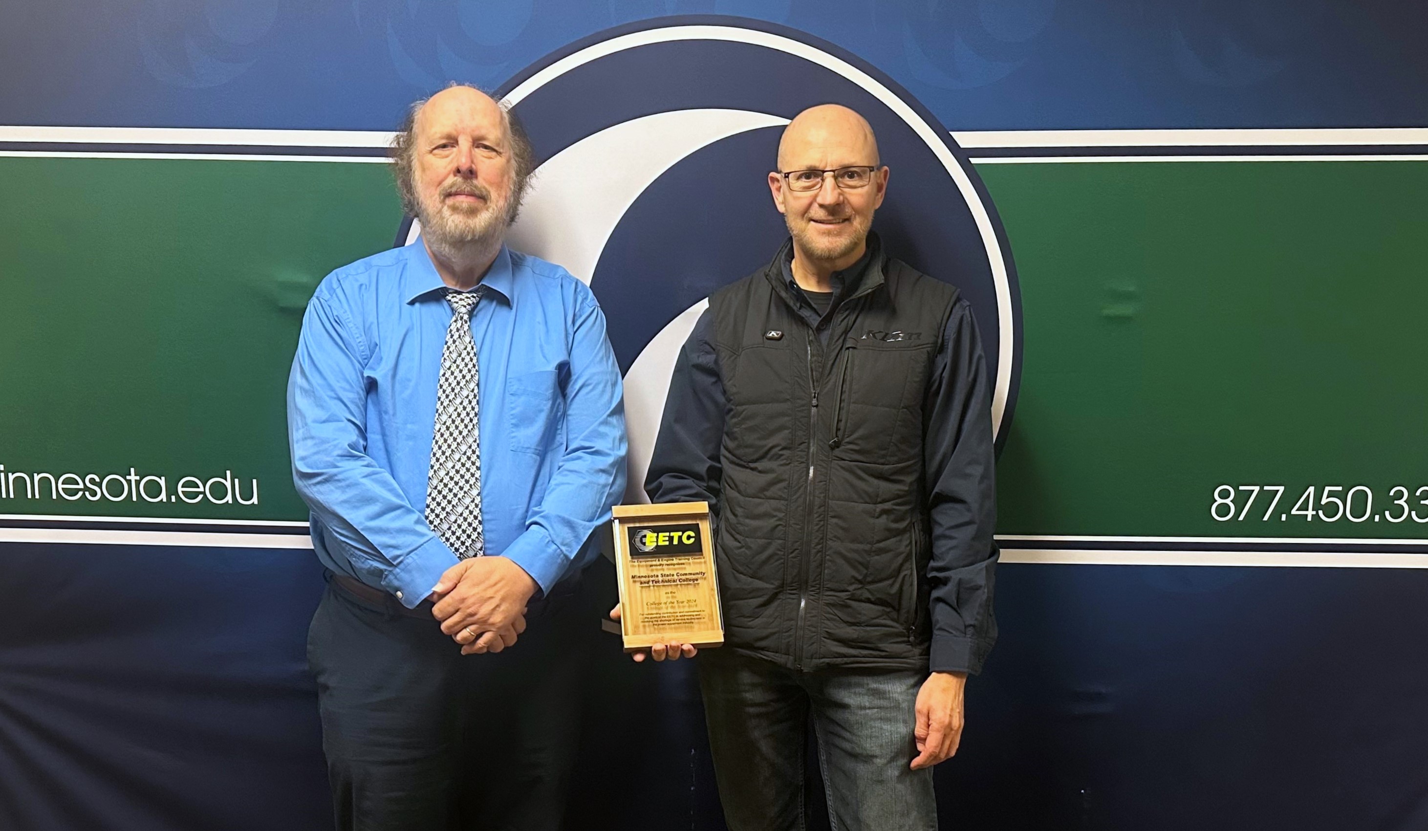 Dr. Mark Bannatyne, Dean for the School of Applied Technology at M State, and Kent Reisenauer, PowerSports Technology Faculty, pose with the 2024 College of the Year award from the national Equipment and Engine Training Council. 