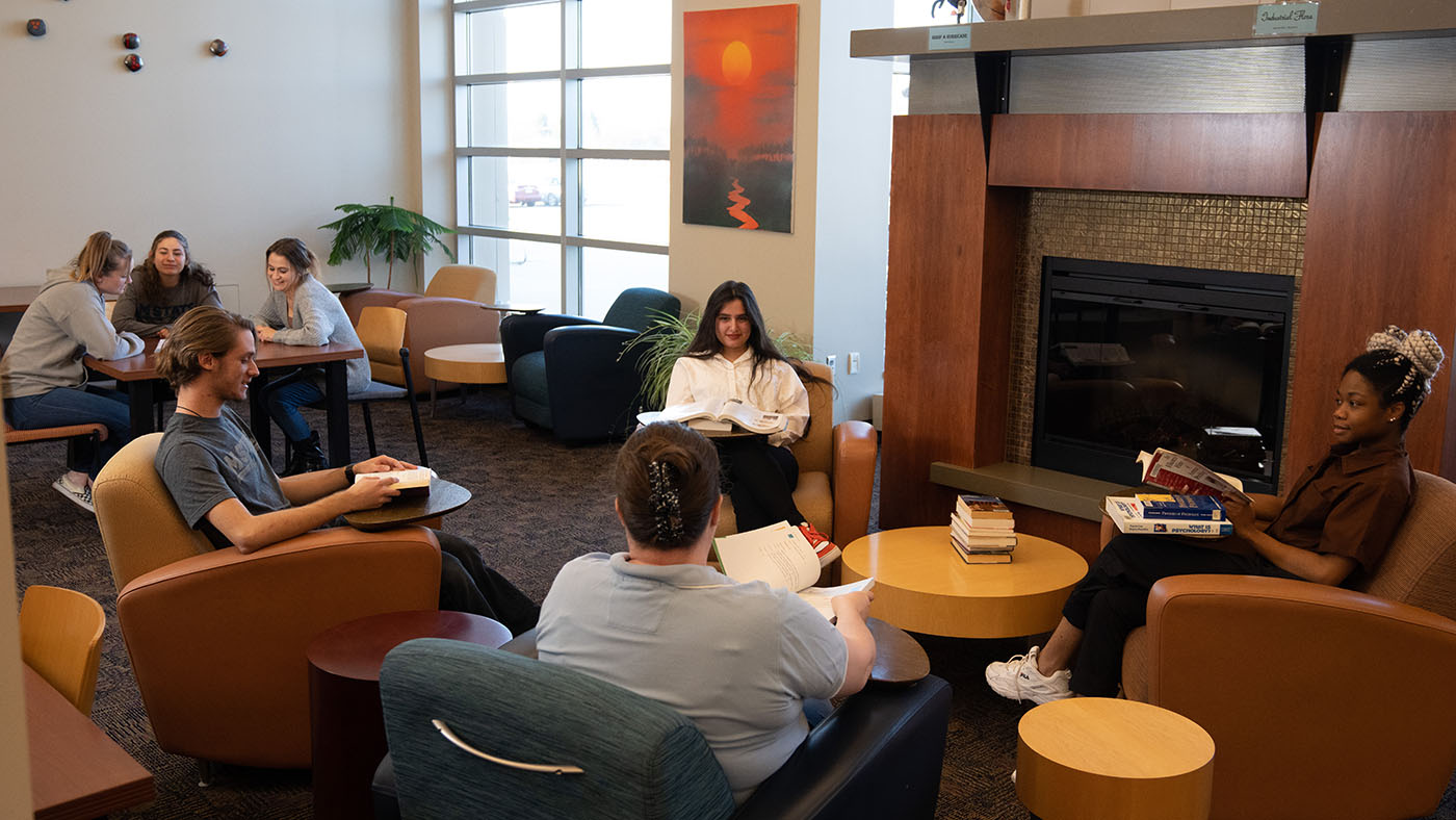 Students sitting by a fireplace talk and study