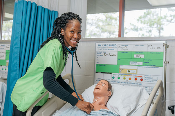 A nursing student works on a mannequin