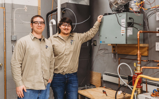 Two men smiling in front of metal hvac box