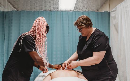 A massage therapy student practicing the art of hot rocks