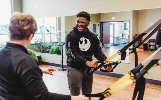 Photo of a student and instructor using work out equipment in the fitness center