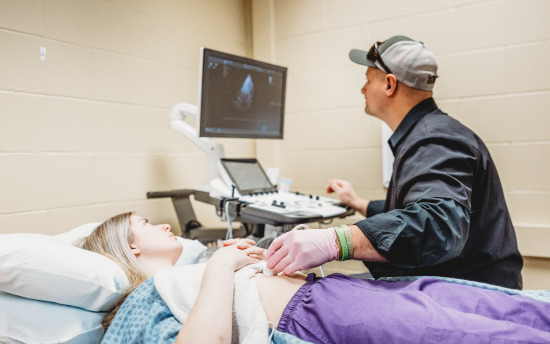 a person lying in a hospital bed with an ultrasound machine next to them