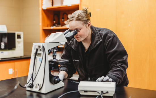 a person in a lab looking through a microscope