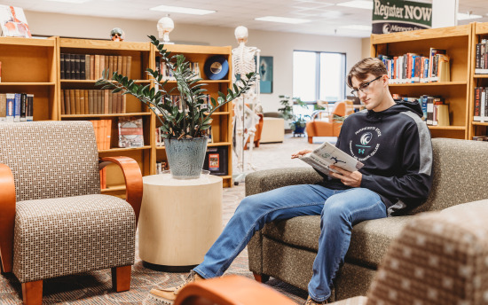 A student reading a book in a study area of the library