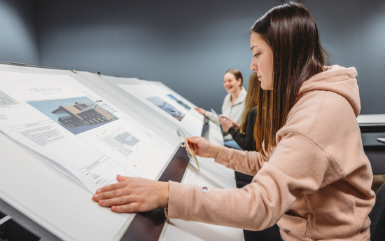 Three students reviewing blueprints for the architectural drafting and design program