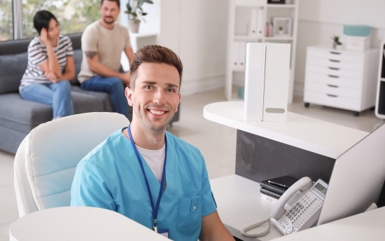 A medical employee looks up from working at a computer