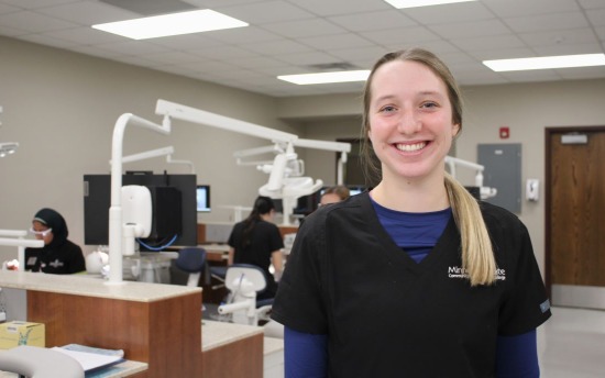 Shae Cossette, Dental Hygiene student, in blue uniform with exam equipment in background