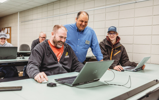 An instructor observes a student on a laptop