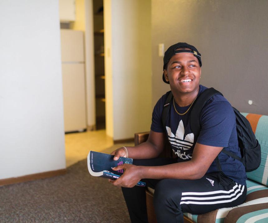 A seated student in M State housing smiles