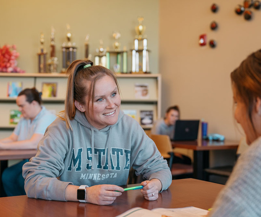 Two people sit at a table in an M State library