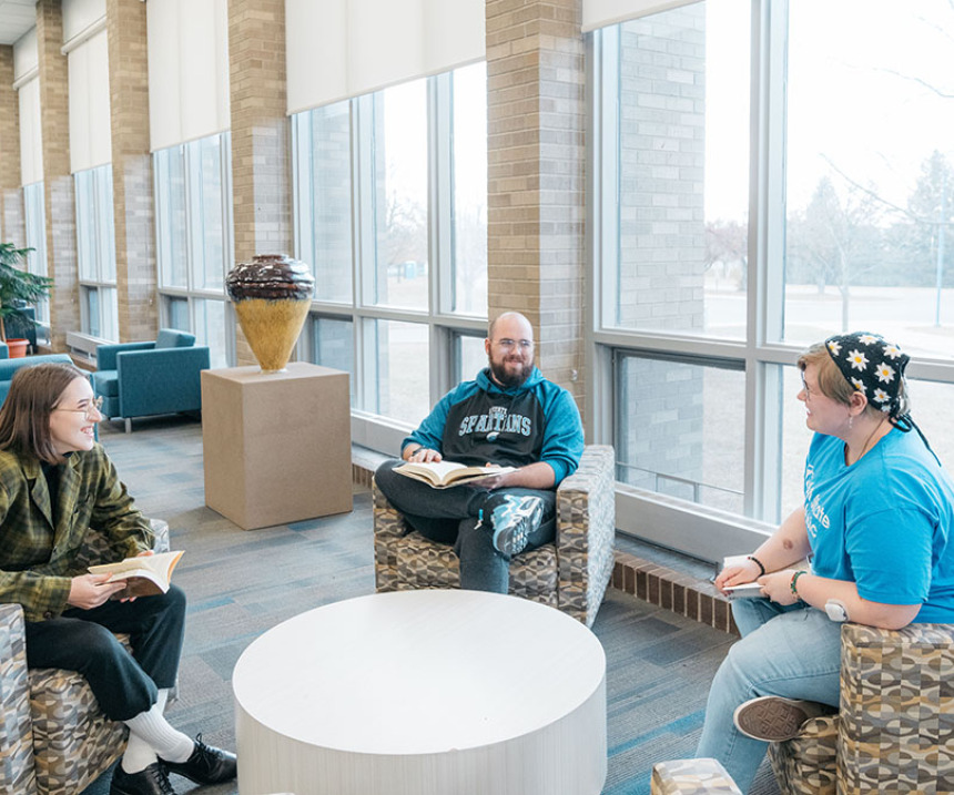 Three people sit in a lounge talking