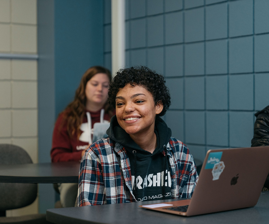 A student in a flannel shirt smiles in class